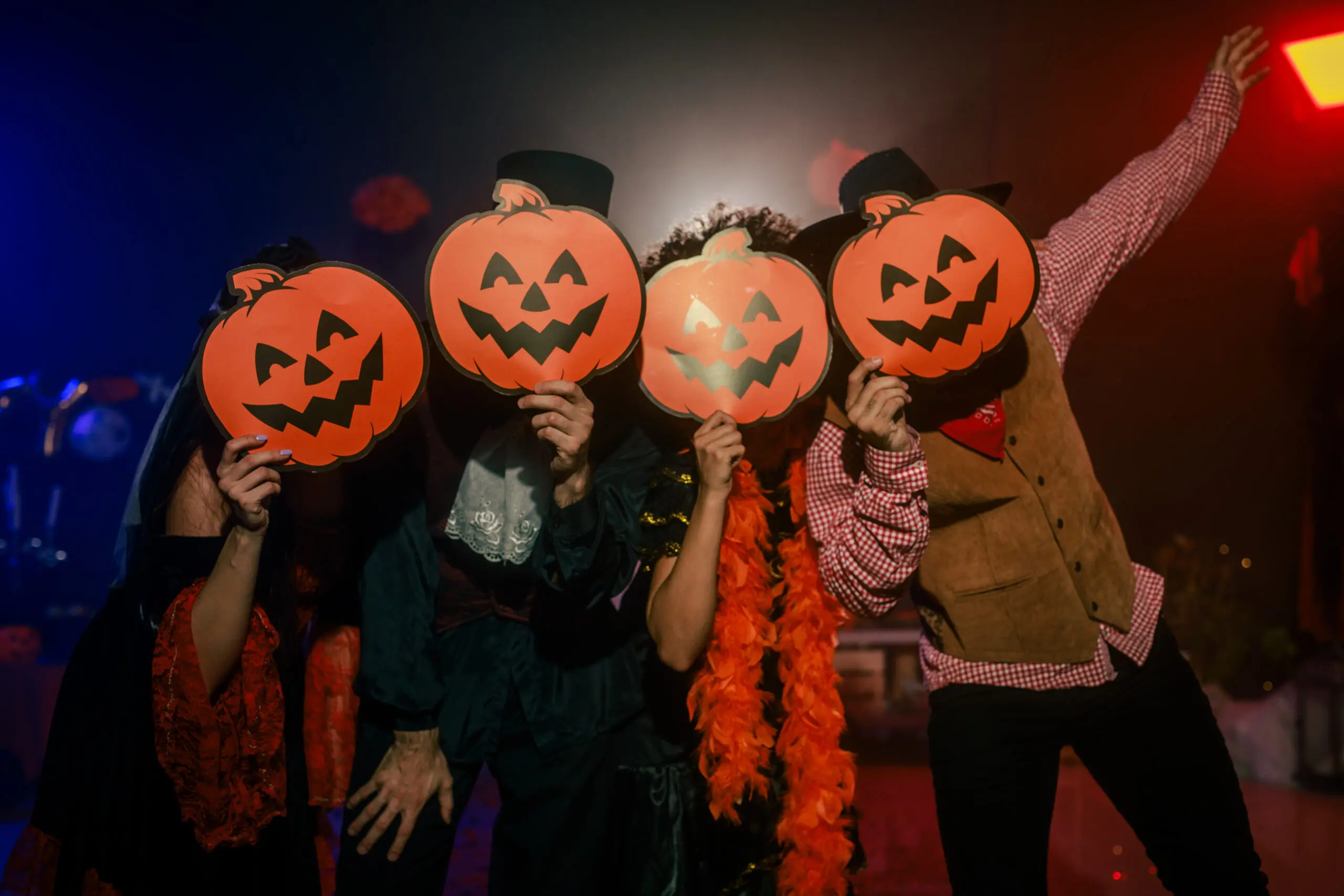 Amigos poniéndose máscaras de Jack o' Lantern sobre las caras durante una fiesta de Halloween