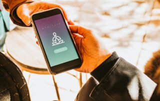 Hand holding a smart phone that displays a meditation app.