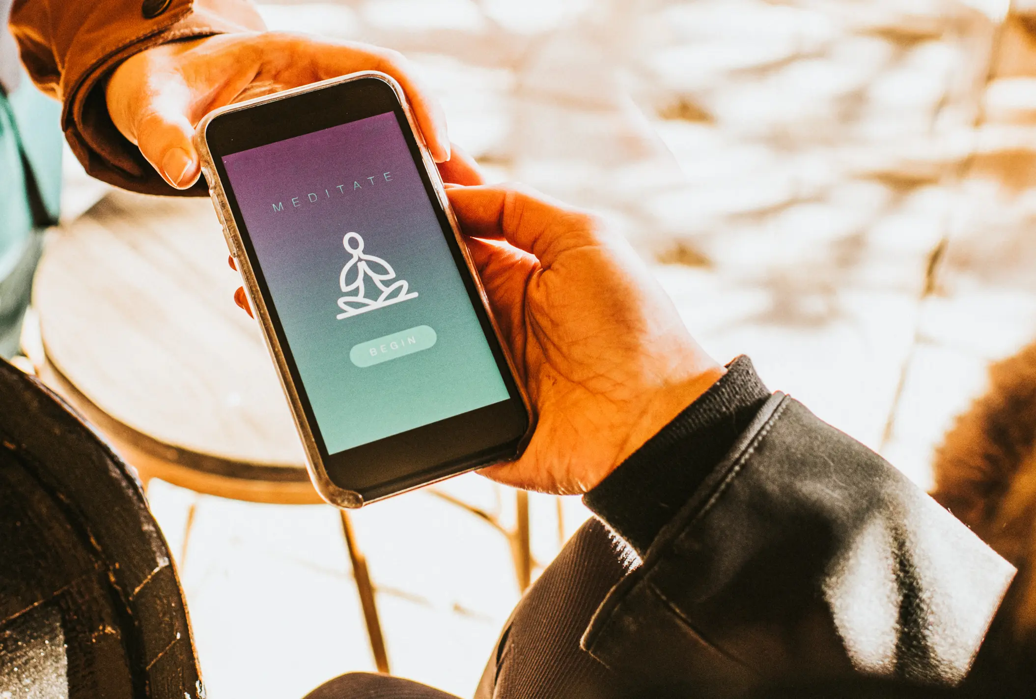 Mano sosteniendo un teléfono inteligente que muestra una aplicación de meditación.